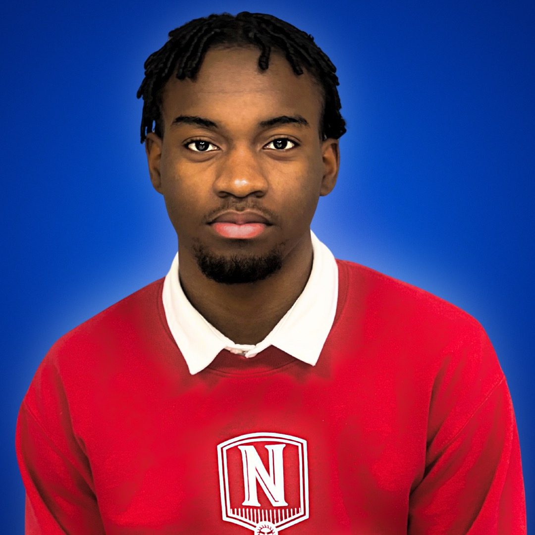 This photo is a headshot of Emmanuel Poe, a student at Johnson College Prep. He is a young Black man with short locs. In this photo, he is wearing a bright red sweatshirt with the Johnson logo on top of a white collared shirt.