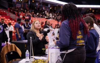 Photo shows Mari Santillan, a Pritzker College Prep alum, talking with current Noble students at the annual Junior College Fair. She is now the assistant director of admissions at DePauw University.