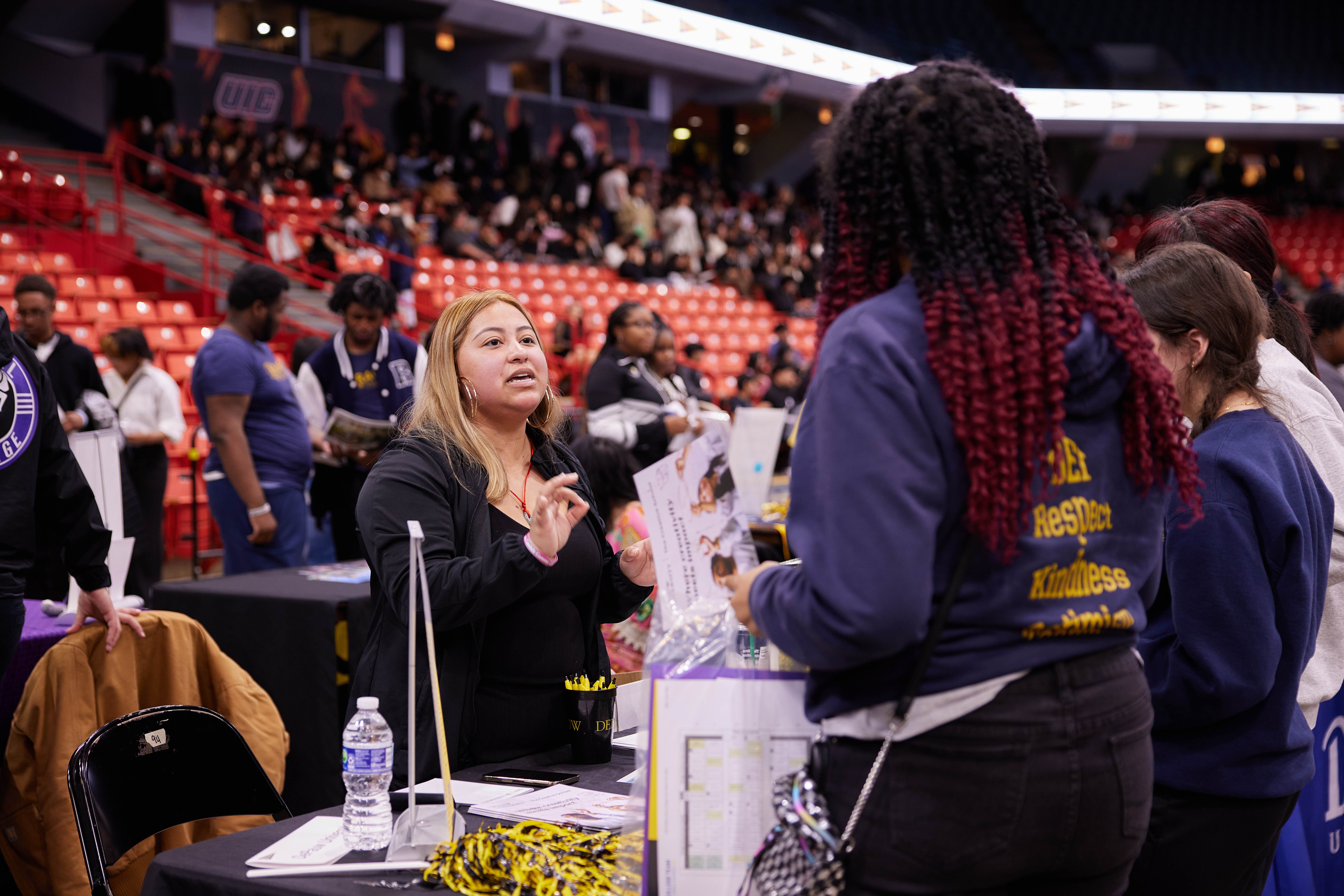 Photo shows Mari Santillan, a Pritzker College Prep alum, talking with current Noble students at the annual Junior College Fair. She is now the assistant director of admissions at DePauw University.